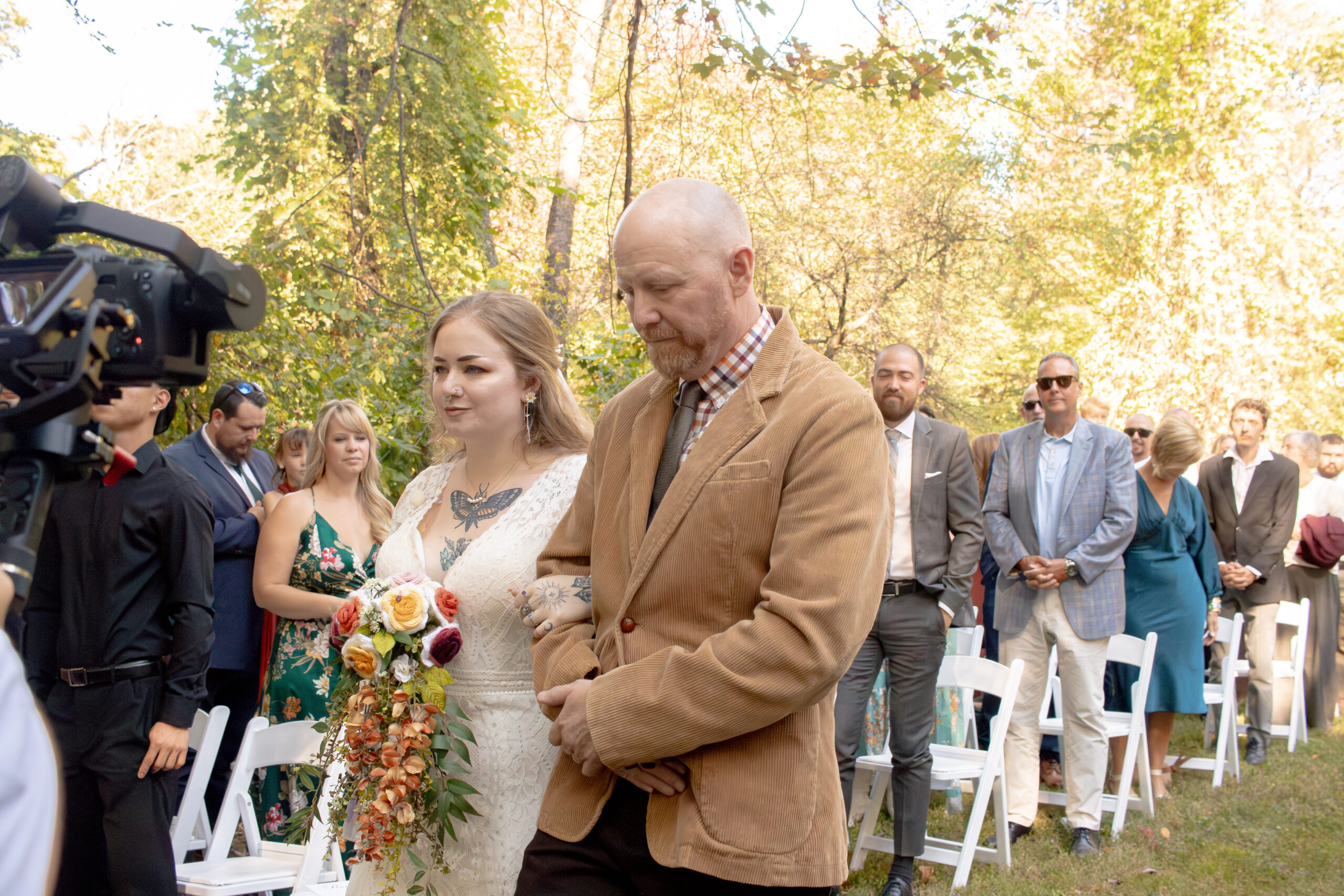 Bride escorted down an outdoor wedding aisle as guests look on