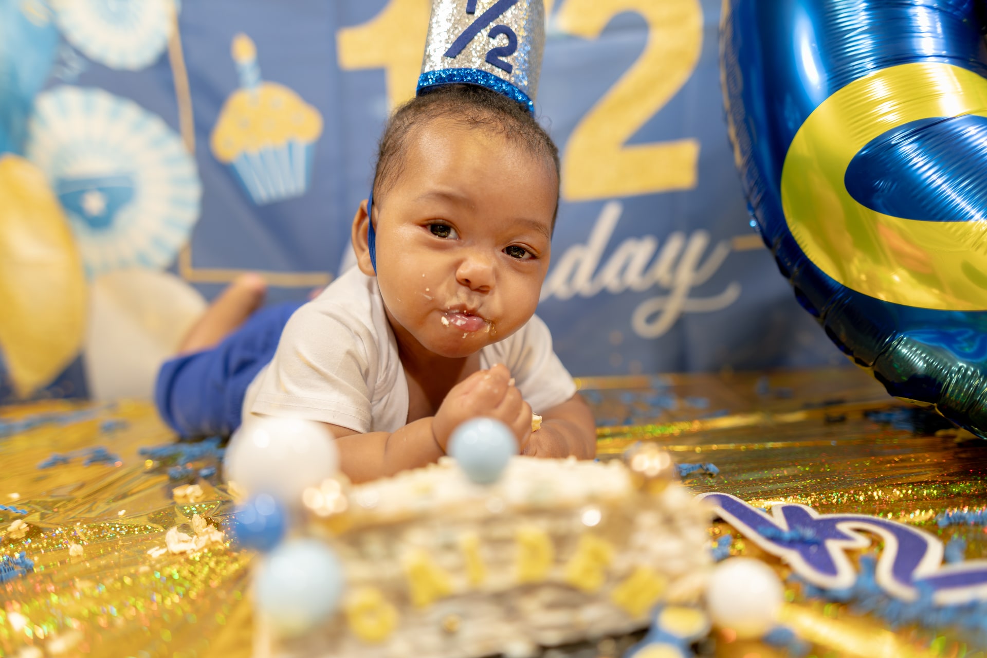 Caiden looking at the camera with frosting on the lips and a cake in front